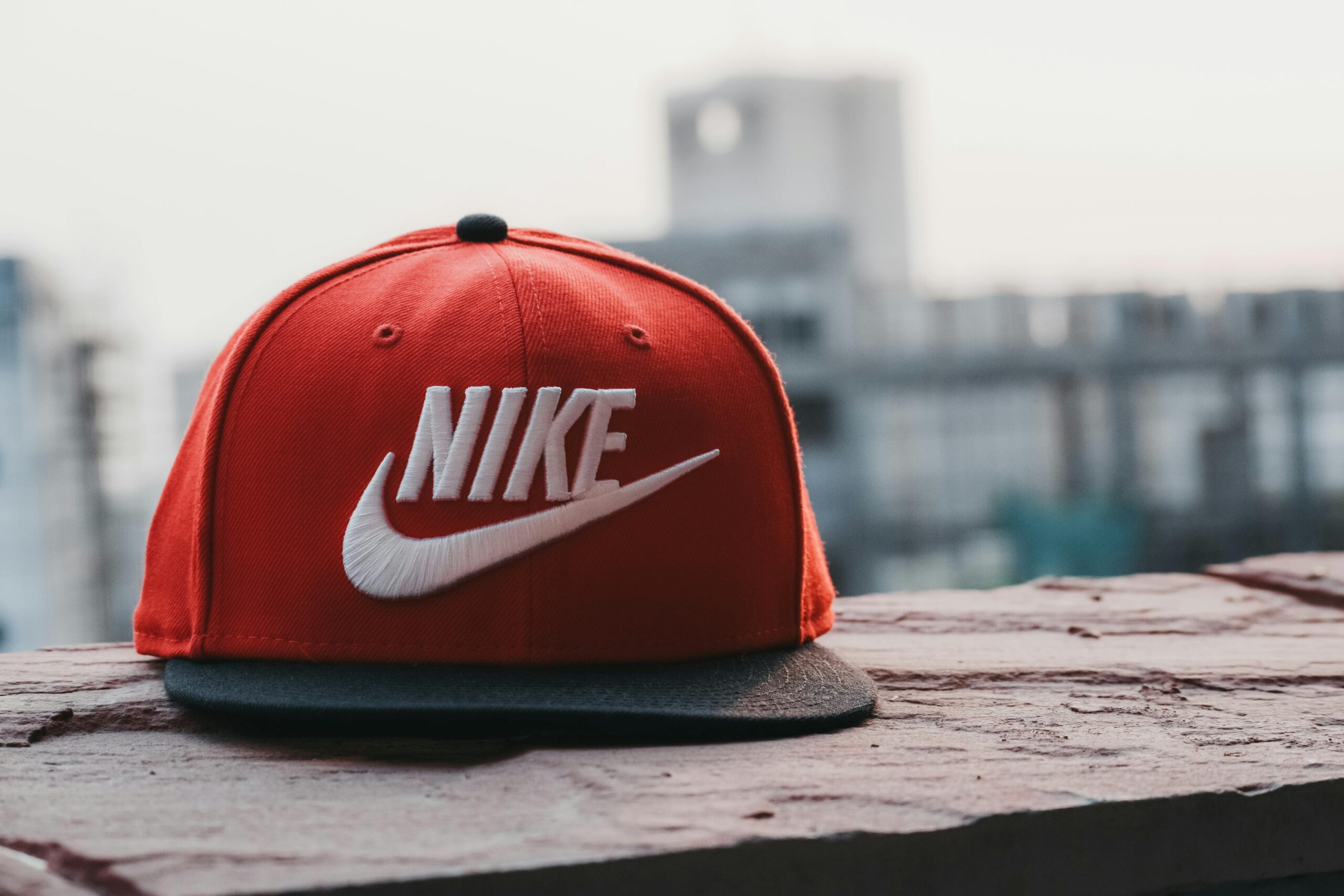 Red cap with logo on a rooftop against an urban cityscape backdrop in daylight.